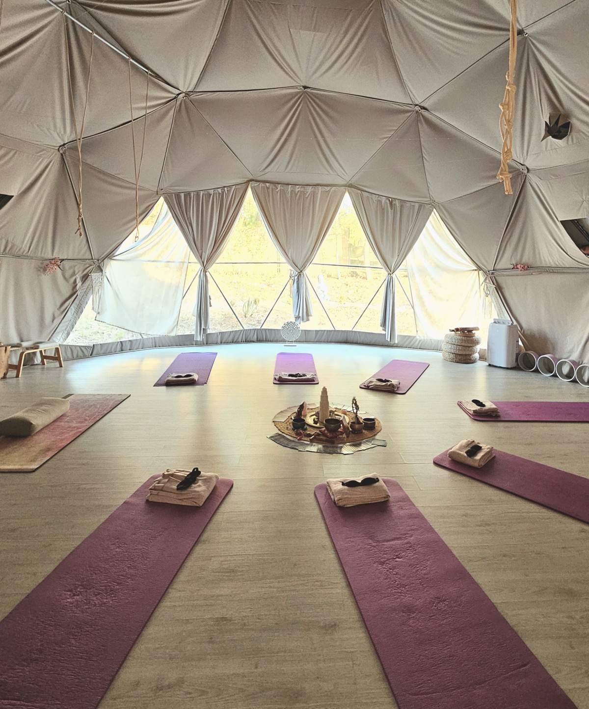 A sunlit geodesic dome prepared with mats for a group practice