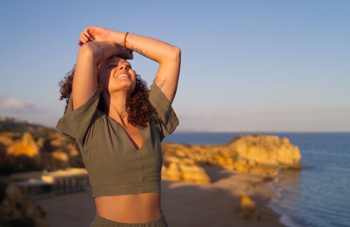 Liza smiling with her eyes closed beside the Algarve coast