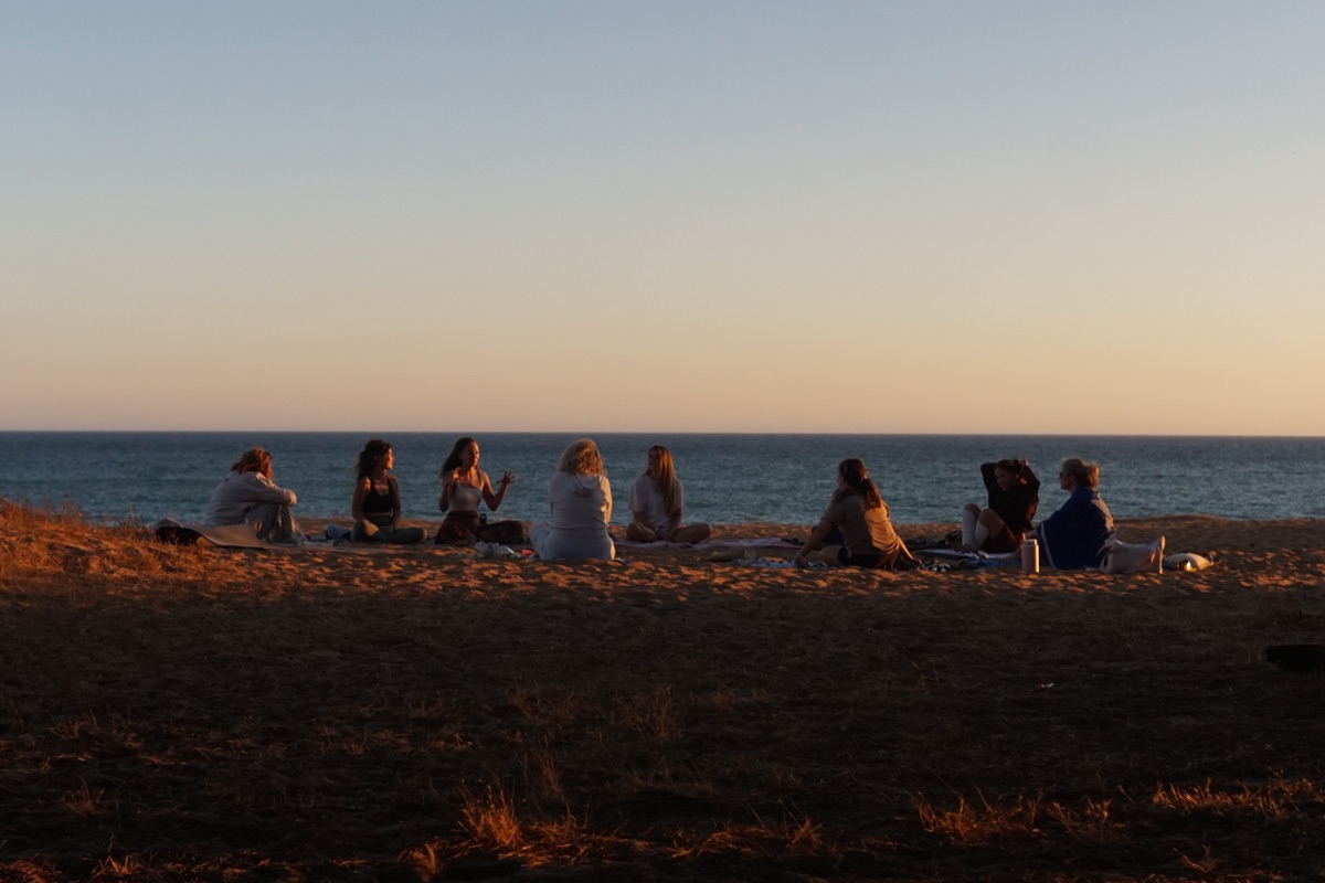 A group sitting together by the ocean at sunset
